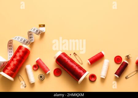 Thread spools, buttons and measuring tape on color background Stock Photo
