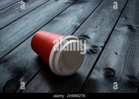 Red paper disposable cup on a dark wooden table in a cafe. Selective focus. Stock Photo