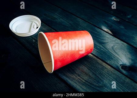 Empty paper disposable cup on a dark wooden table in a cafe. Selective focus, copy space. Stock Photo