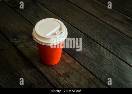 Paper disposable cup with coffee on a wooden table in a cafe. Selective focus. Stock Photo