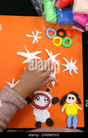 YUNCHENG, CHINA - FEBRUARY 10, 2022 - Children make 'Bing Dwen Dwen' and 'Xue Rong Rong' with handmade clay in Yuncheng City, Shanxi Province, China, Stock Photo