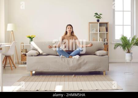 Calm woman practice yoga meditate on couch Stock Photo