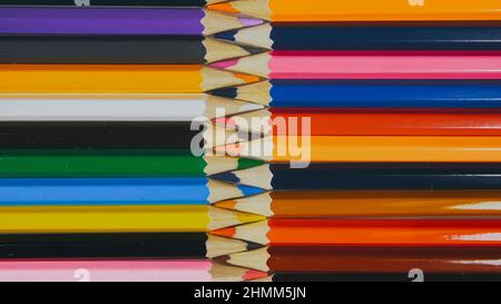 Many colored pencils are arranged around the edges of the image as a frame. In the center is an empty background with space for text. Mock up with copy space. Stock Photo
