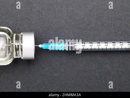 Liquid medicine in vials and injection syringe on dark gray background Stock Photo