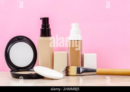 Liquid fluid foundation glass bottle on makeup sponges and brush makeup on pink background. Stock Photo