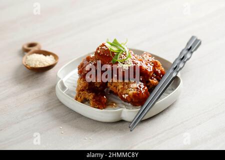 Yangnyeom Tongdak Korean Spicy Deep-Fried Chicken Topped White Sesame with on the Grey Concrete Table, Popular Street Food in Korea. Stock Photo