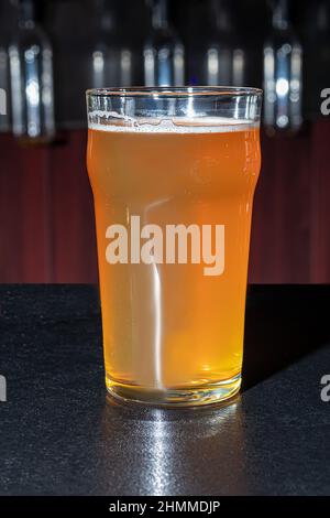 Glasses with different types of craft beer on a wooden bar. In glasses and bottles. Nuts and crackers on the table. On a dark background. copy space Stock Photo