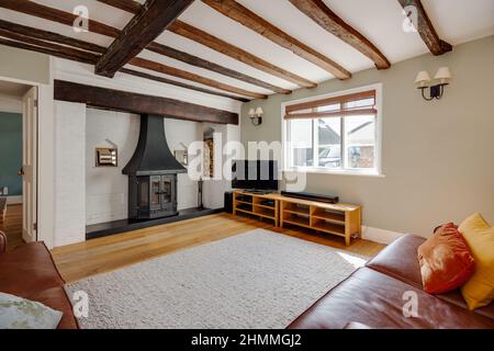 Great Chesterford, Essex - April 3 2017 - Very stylish fashionably furnished and decorated old cottage living room with white painted fireplace Stock Photo