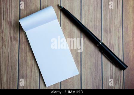 Notepad with a pen on a wooden desk. Directly above. Flat lay. Stock Photo