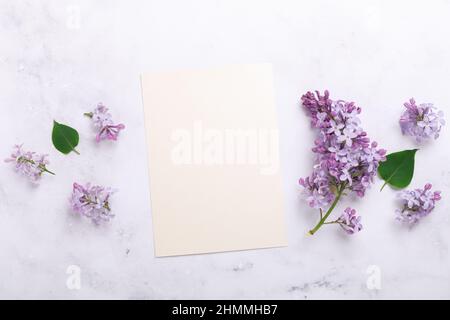 Flowers composition. Sheet of paper and lilac flowers on stone background. Template for your invitation or greeting card. Flat lay, top view Stock Photo