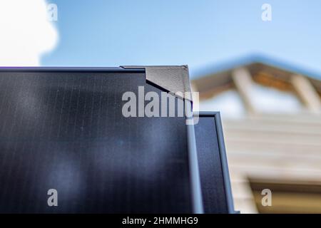 Close-up of an installation of an array of solar panels, installed on top of a house with roof tiles. Stock Photo