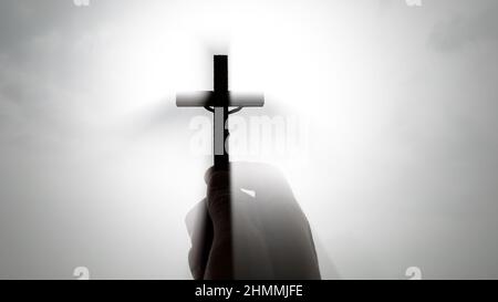 Hand holding Holy Cross with bright sky background. Christian concept Stock Photo