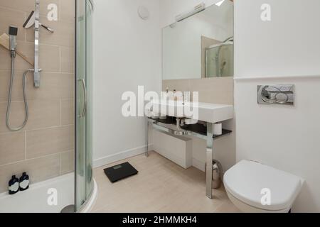 Newport, Essex - July 10 2018: Luxury shower room in white with tiled show cubicle and large ceramic sink on chromed steel frame Stock Photo