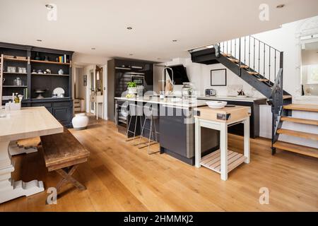 Newport, Essex - July 10 2018: Ultra modern fashionable chic kitchen with breakfast bar and dining table decorated and finished in shade of whites, gr Stock Photo