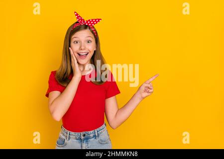 Portrait of adorable kind sweet little teen woman impressed face expression promote offer isolated on yellow color background Stock Photo