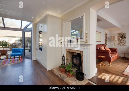 Hemingford Grey, Cambridgeshire - Feb 10 2018: Stylish luxury kitchen with fireplace and wood burner stove on brick hearth open to sitting room lounge Stock Photo