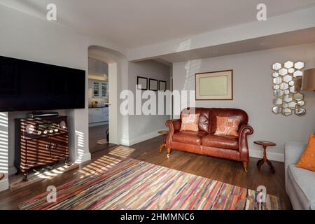 Hemingford Grey, Cambridgeshire - Feb 10 2018: Sunlit stylish fashionable chic living room simply furnished with open arch leading to kitchen. Stock Photo