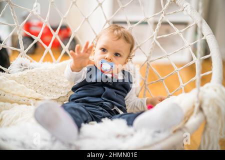 Image of cute baby boy with pacifier sitting . Stock Photo