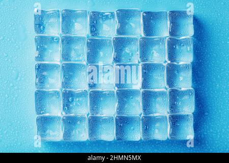 Ice made of cubes lined up with drops on a blue background Stock Photo