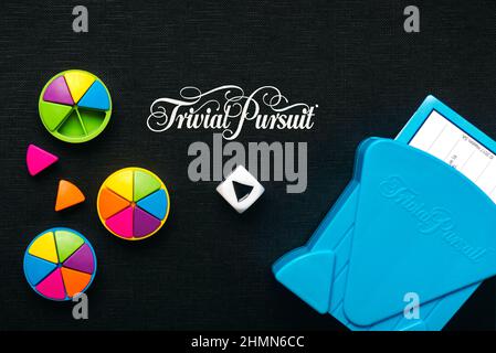 Black board game of Trivial Pursuit game with white die,colored plastic pieces and blue card holder Stock Photo