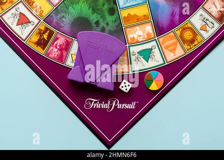 Board game of Trivial Pursuit game with white die,colored plastic pieces and purple card holder over blue background Stock Photo