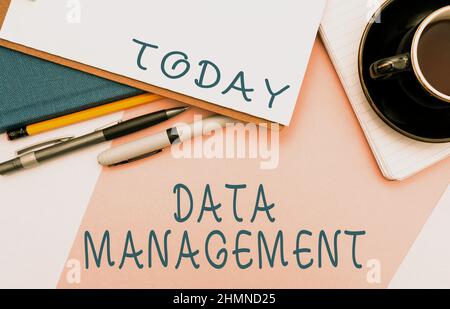 Writing displaying text Data Management. Word for The practice of organizing and maintaining data processes Office Supplies Over Desk With Keyboard Stock Photo