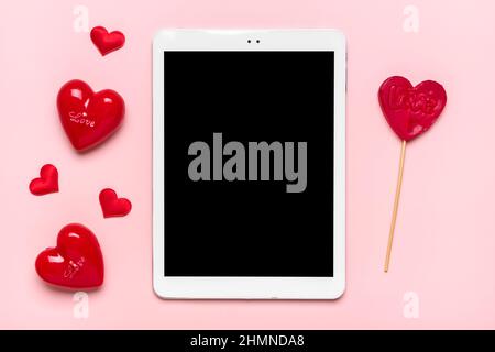 tablet for chooses gifts, makes purchase, two red hearts on pink table Top view Flat lay Holiday shopping list, Happy Valentine's day, party, online Stock Photo