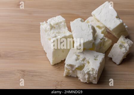 Soft white cheese cubes on wooden board with copy space - feta cheese Stock Photo