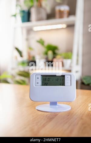 A front-view shot of a thermostat on a wooden table in a home. Stock Photo