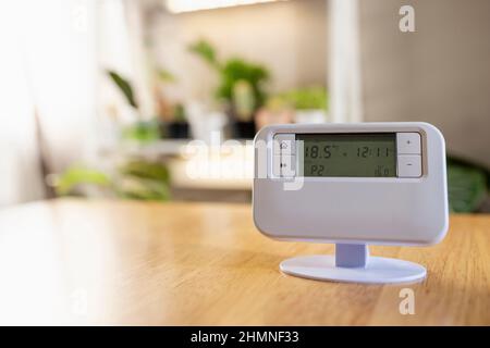 A front-view shot of a thermostat on a wooden table in a home. Stock Photo