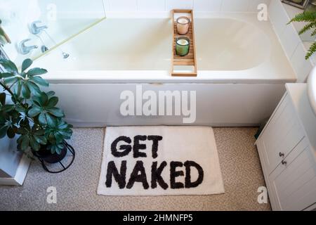 A high angle wide-view shot of a modern bathroom interior decorated with houseplants and a funny bathroom mat. Stock Photo