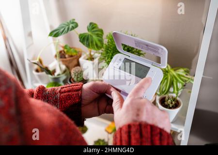 A point of view shot of an unrecognisable man holding a thermostat in his home. Stock Photo