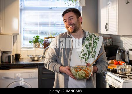 A front-view shot of a caucasian man standing in his kitchen, he has made a bowl of pasta for lunch. Stock Photo