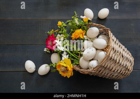 Easter Holiday. Quail egg in a wicker basket, blue wooden table background, top view. Spring flower decoration Stock Photo