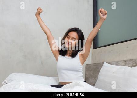 Young asian beautiful woman stretching happy and relaxed after wake up feel fresh at home Stock Photo