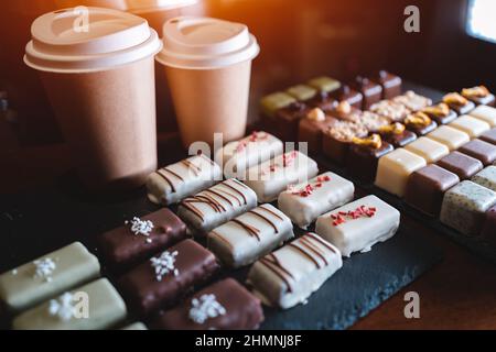 set of delicious handmade chocolate candies with coffee to go in paper cup Stock Photo