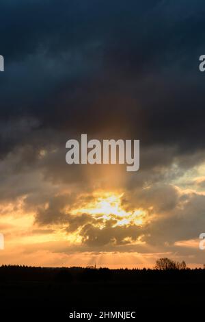 Sunrise with sunrays through dark clouds Stock Photo