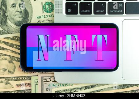 NFT non fungible token background. Modern blockchain technology, future of crypto art and crypto currency. Mobile phone on laptop keyboard, top view Stock Photo