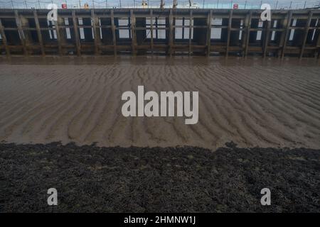 Region of unstable silt demarks area between pier and foreshore where seaweed cannot grow due to silt and currents Stock Photo