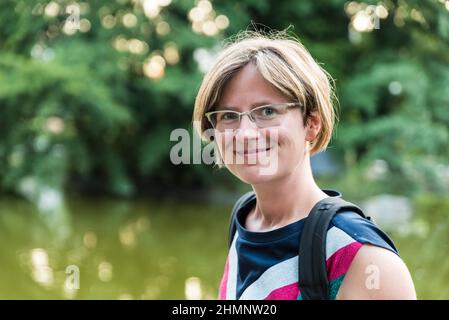 Backlight portrait of a 30 year old woman with a bokeh nature background Stock Photo