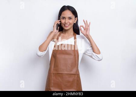 Young asian woman bartender or waitress using mobile smartphone isolated on white background Stock Photo
