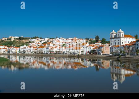 Romantic Mediterranean village with white houses with red tiled roofs are reflected in water, embankment of small town peaceful Alcacer do Sal, Alente Stock Photo