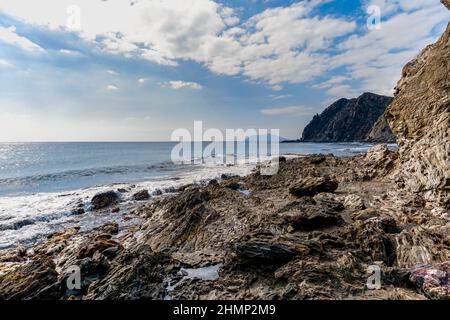 A wild mountainous coastline with rocks and tidal pools in the foreground Stock Photo