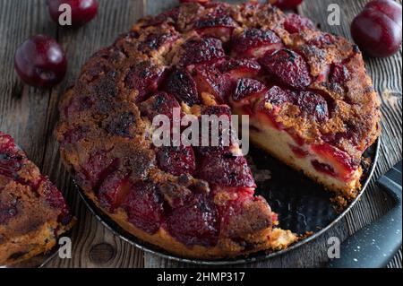 Rustic plum cake baked up side down and served isolated on wooden table Stock Photo