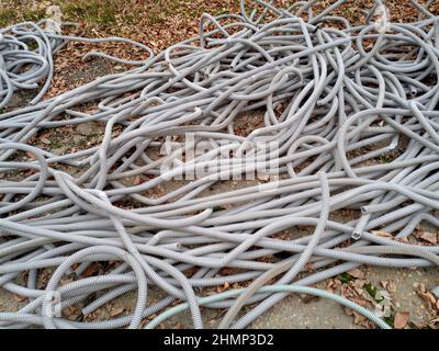 Corrugated pipes for electrical wiring lie in a heap on the ground. Stock Photo