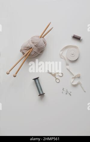 Top view of scissors, threads, knitting needles and sewing supplies on a white background. Concept of craft hobby, knitting and sewing Stock Photo