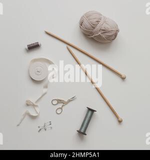 Top view of scissors, threads, knitting needles and sewing supplies on a white background. Concept of craft hobby, knitting and sewing Stock Photo