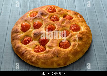 Apulian focaccia, typical italian Bari pizza made with a dough of durum wheat flour and potatoes with cherry tomatoes on top. on light blue wooden tab Stock Photo