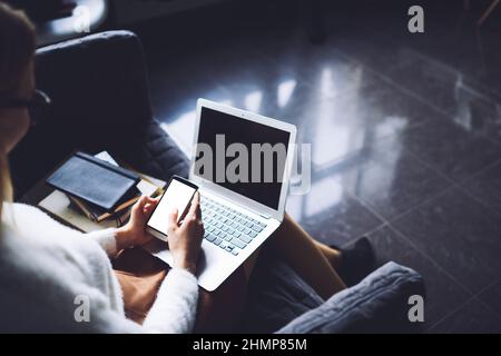 Faceless lady working on smartphone and laptop in library Stock Photo