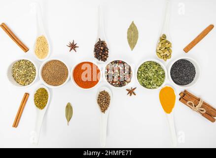 Seasonings for food. Set of different culinary spices in white ceramic bowls and spoons, on a white background. Stock Photo